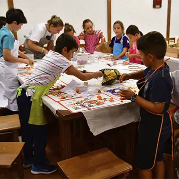 Niños disfrutando en un taller de cocina dentro de una sociedad gastronómica.