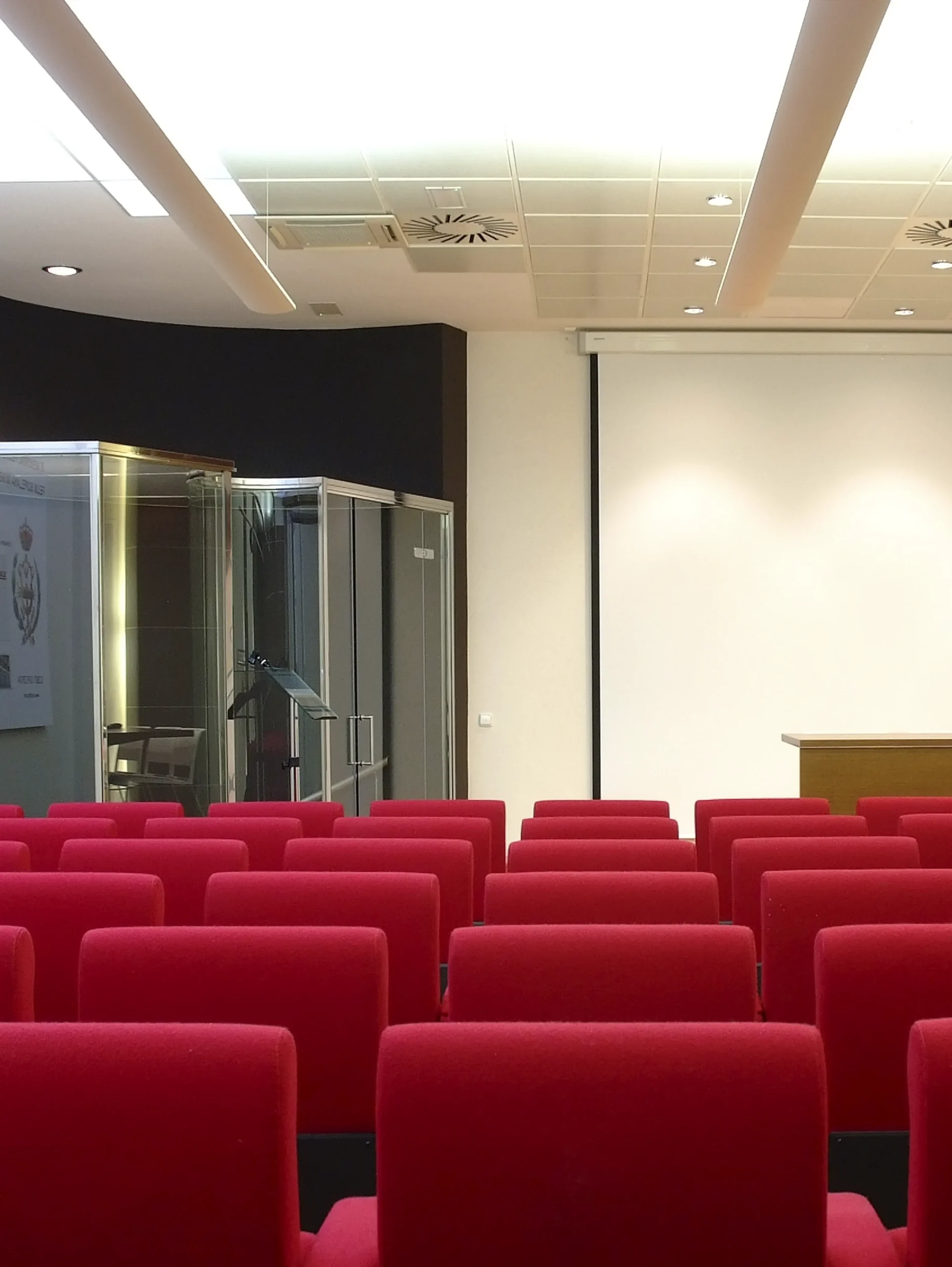 Sala de actos con butacas rojas vacías 